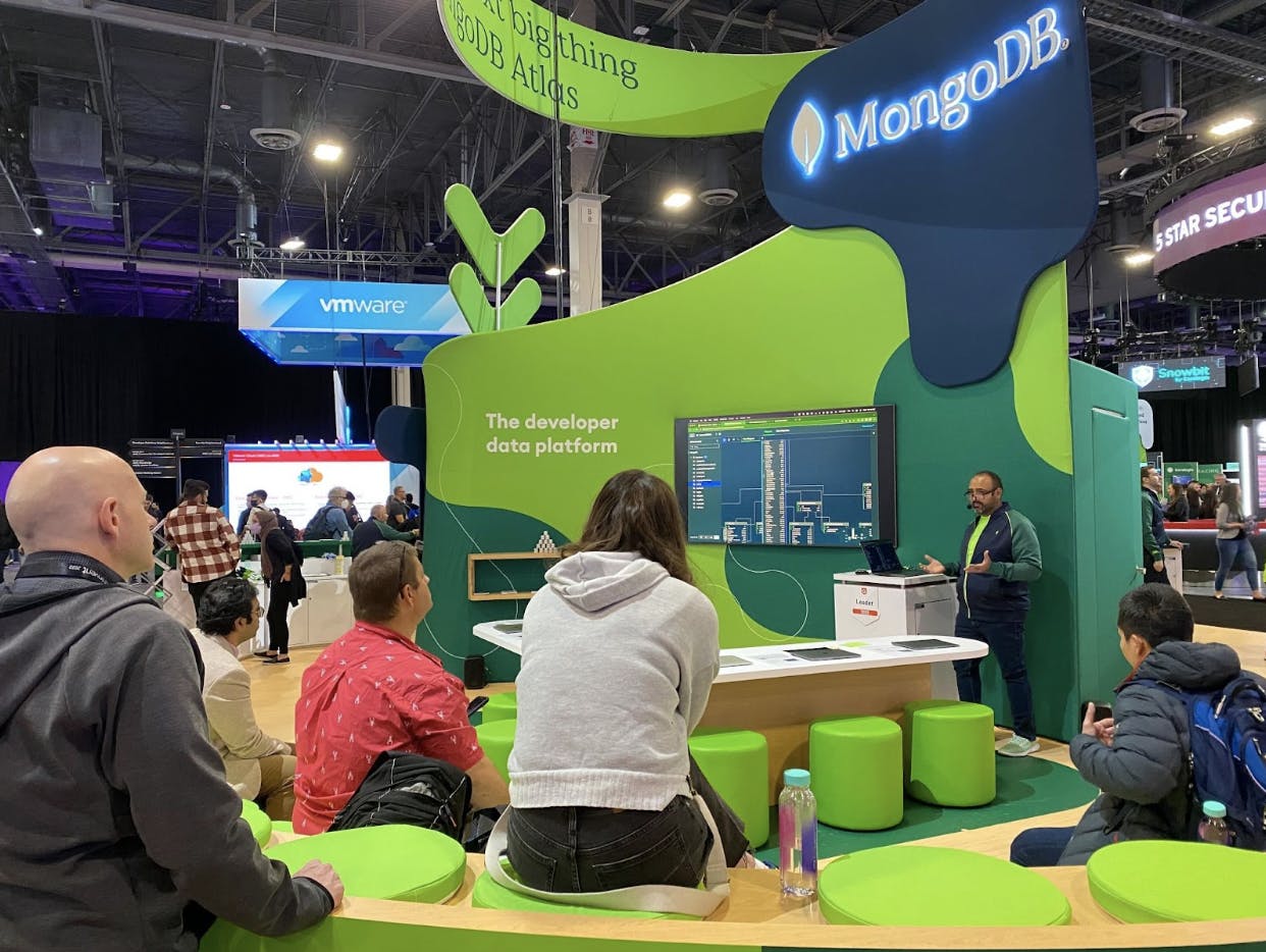 MongoDB executive solutions architect Sigfrido Narváez gives a demonstration to a small group in the green-and-lime MongoDB booth.