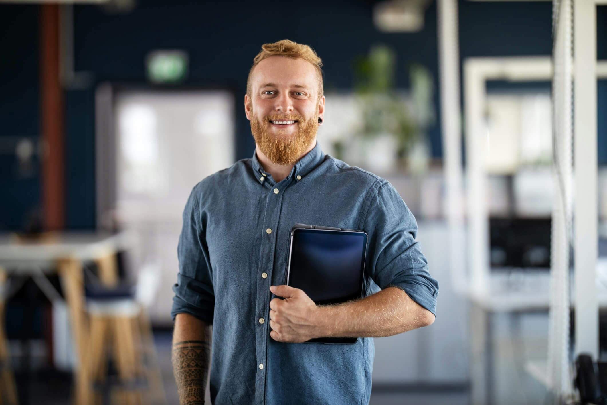Man standing in an office with a tablet in his hand
