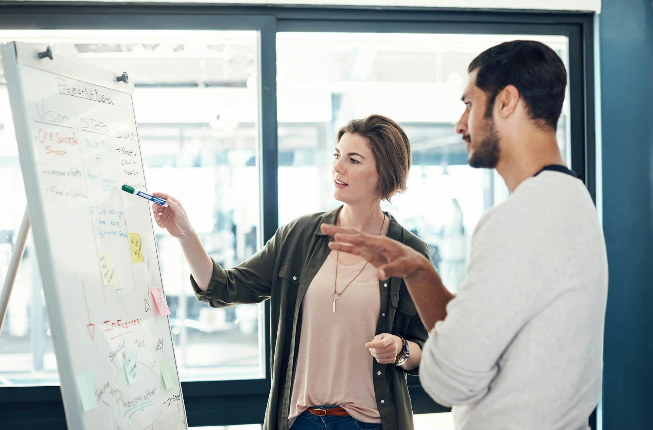 Man and woman in an office looking at a whiteboard